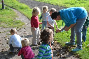 Ein Erzieher erkundet mit Kindern Pflanzen am Wegesrand